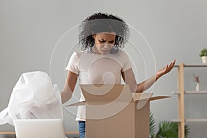 Disappointed shocked african woman open cardboard box receive bad parcel