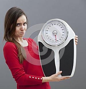 Disappointed smart 20 girl holding scales for checking weight loss