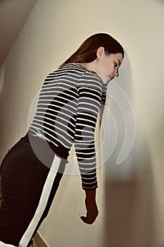 Disappointed teenage girl with hands leaning against a white wall. Sad girl leaning against wall.