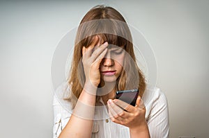 Disappointed woman holding and looking on mobile phone