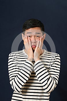 Disappointed young Asian man covering his face by palms