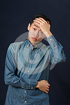 Disappointed young Asian man covering his forehead by palm