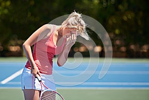 Disappointing serve. A tennis player putting her head in her hand whilst holding a tennis racket.