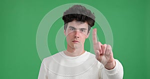 Disapproving Caucasian Man Shaking Finger in Denial on Green Background