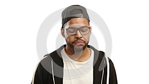 Disapproving young multiracial man shaking head in glasses and cap