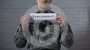 Disarmament word written on sign in hands of male soldier, end of war, peace