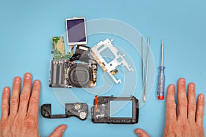 Disassembled camera, tools and repairman's hands
