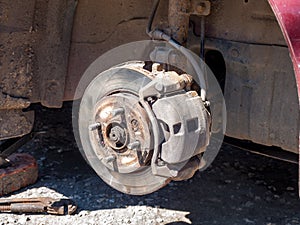 Disassembled car wheel, view of the brake caliper and disc, shock absorbers and suspension springs of the car, service and repair