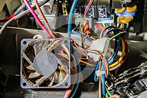Disassembled computer power supply unit. Dusty cooling fan close-up.