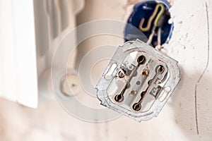 Disassembled electrical outlet in detonation wall with bare wires and hallmarks during repair in apartment