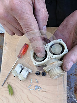 Disassembled electrovalve in hands outdoors