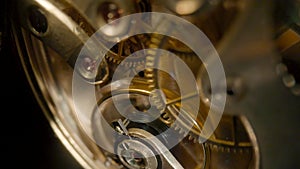 Disassembled gold pocket watch with clockwork turning. Working clock mechanism with rotating spring, gears, gearing and