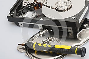 The disassembled hard drive next to the tools with which it was disassembled