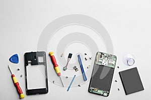 Disassembled mobile phone and repair tools on background, flat lay