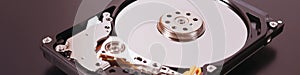 A disassembled open hard disk drive HDD of computer or laptop lies on brown matte surface. IT close-up. Banner about computer