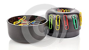 Disassembled on two parts cylindrical black plastic magnetic holder with colored paper clips isolated on white background