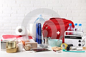 Disaster supply kit for earthquake on white wooden table near brick wall