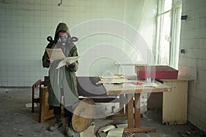 Disaster survivor in a post apocalyptic setting, she is wearing a gas mask and reading document. Environmental pollution