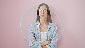 Disbelieving portrait of a beautiful young hispanic woman, crossed arms, sporting casual wear over pink backdrop. nervous,