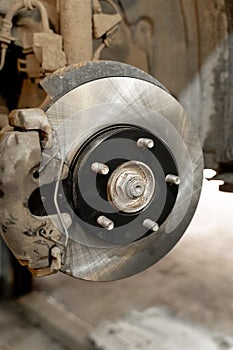 Disc brake on a car, brake disc replacement in a car service. The rim is removed, exposing the rotor and caliper.