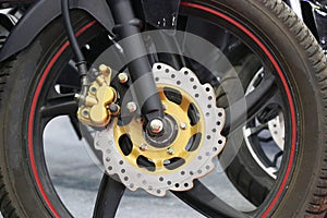 Disc brake of an electric motorcycle. Chrome disc brakes with a modern design and a gold color caliper installed on an electric