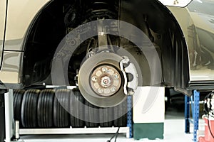 Disc car close up - mechanic unscrewing automobile parts while working under a lifted auto