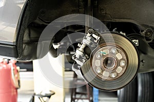 Disc car close up - mechanic unscrewing automobile parts while working under a lifted auto