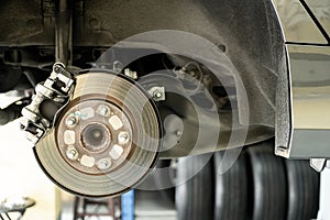 Disc car close up - mechanic unscrewing automobile parts while working under a lifted auto