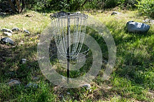 Disc golf cage target, with chains, in a grassy field photo