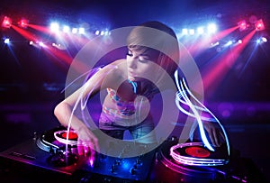 Disc jockey girl playing music with light beam effects on stage