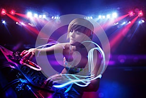 Disc jockey girl playing music with light beam effects on stage