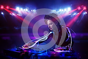 Disc jockey girl playing music with light beam effects on stage