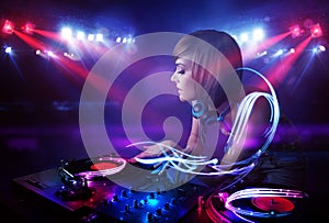 Disc jockey girl playing music with light beam effects on stage