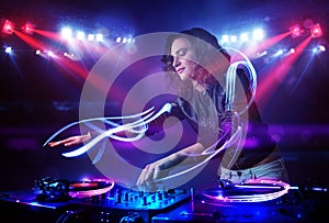 Disc jockey girl playing music with light beam effects on stage