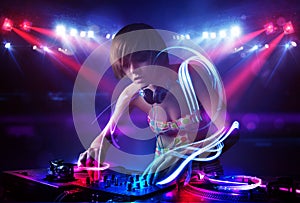 Disc jockey girl playing music with light beam effects on stage