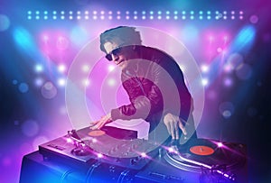 Disc jockey mixing music on turntables on stage with lights and