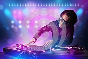 Disc jockey mixing music on turntables on stage with lights and