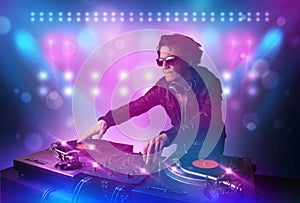 Disc jockey mixing music on turntables on stage with lights and