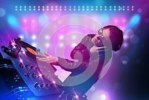 Disc jockey mixing music on turntables on stage with lights and