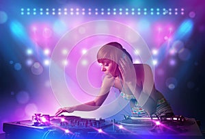 Disc jockey mixing music on turntables on stage with lights and