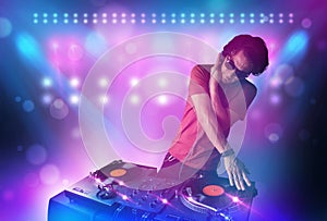 Disc jockey mixing music on turntables on stage with lights and