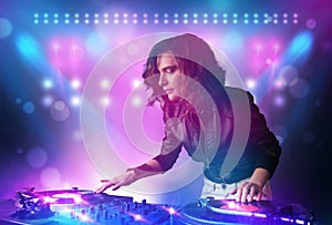 Disc jockey mixing music on turntables on stage with lights and