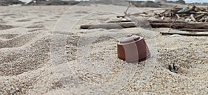 Discarded coffee capsule washed up on sandy beach