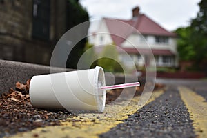 Discarded drinks container lying at the edge of an urban street