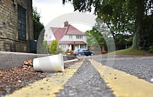 Discarded drinks container lying at the edge of an urban street