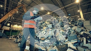 Discarded electronics and a landfill worker inspecting it