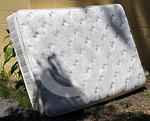 Discarded mattress in alley