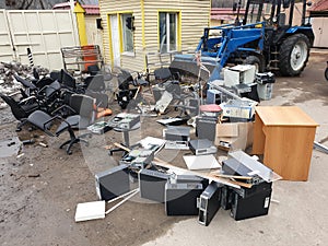 discarded obsolete system units from computers with old office chairs in trash