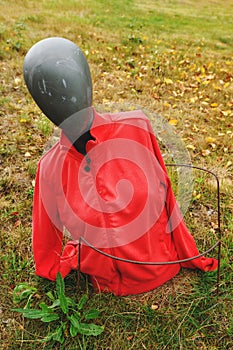 Discarded old mannequin wearing red jacket in public park, concept