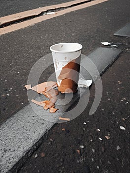 A discarded paper cup torn and stained lying in the street.. AI generation